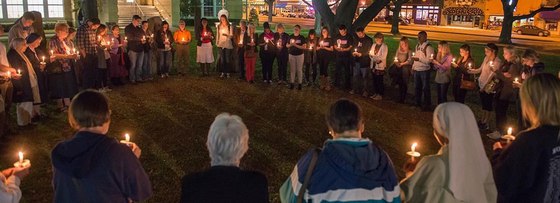 一群拿着蜡烛的人聚集在TCU校园的草坪上进行夜间守夜祈祷.